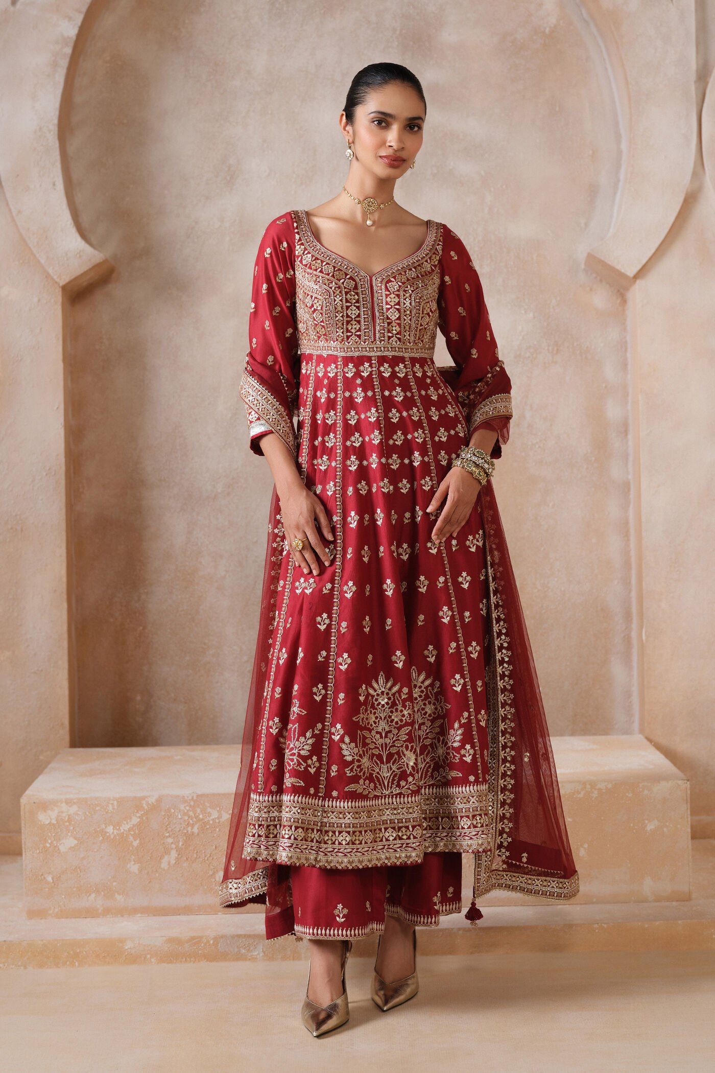 Traditional red Anarkali suit with heavy gold embroidery and matching dupatta for bridal and festive wear.