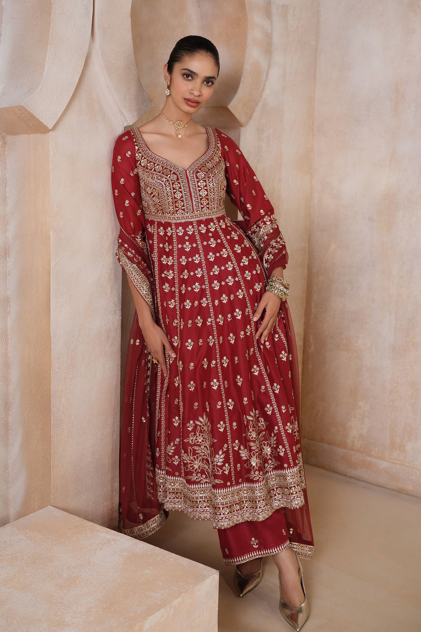 Traditional red Anarkali suit with heavy gold embroidery and matching dupatta for bridal and festive wear.
