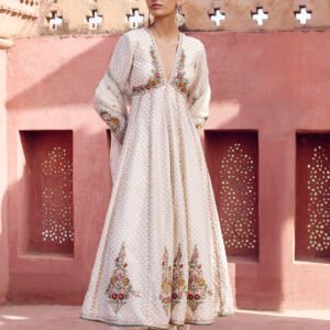Elegant ivory embroidered Anarkali suit with floral embroidery and palazzo pants worn by a woman in a heritage courtyard setting